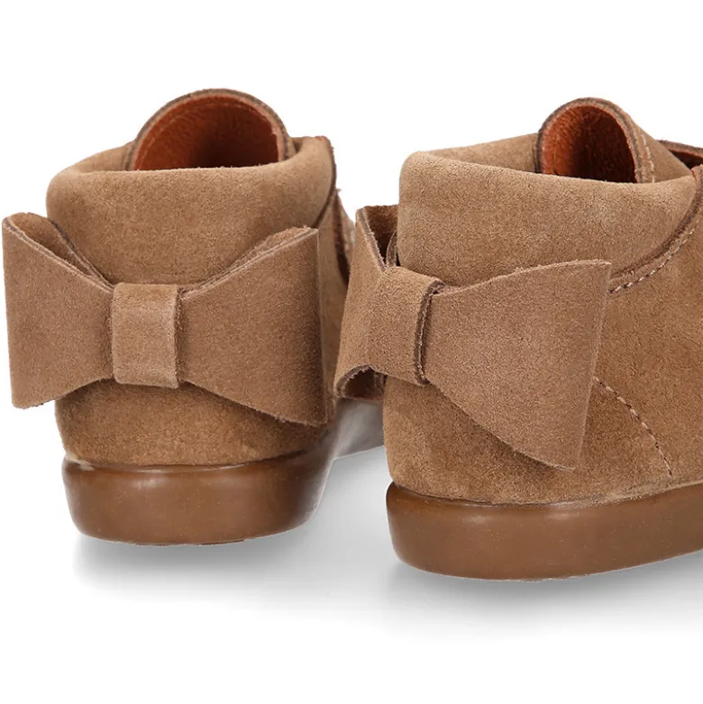 Botita niña sin cordones con lazo y picados en piel serraje.