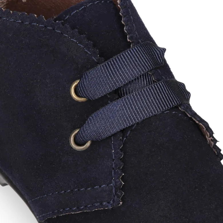 Botín tipo blucher con ondas y lazos en piel serraje.