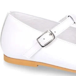 Mercedita niña Okaa en forma de T con picados en piel charol en color blanco.