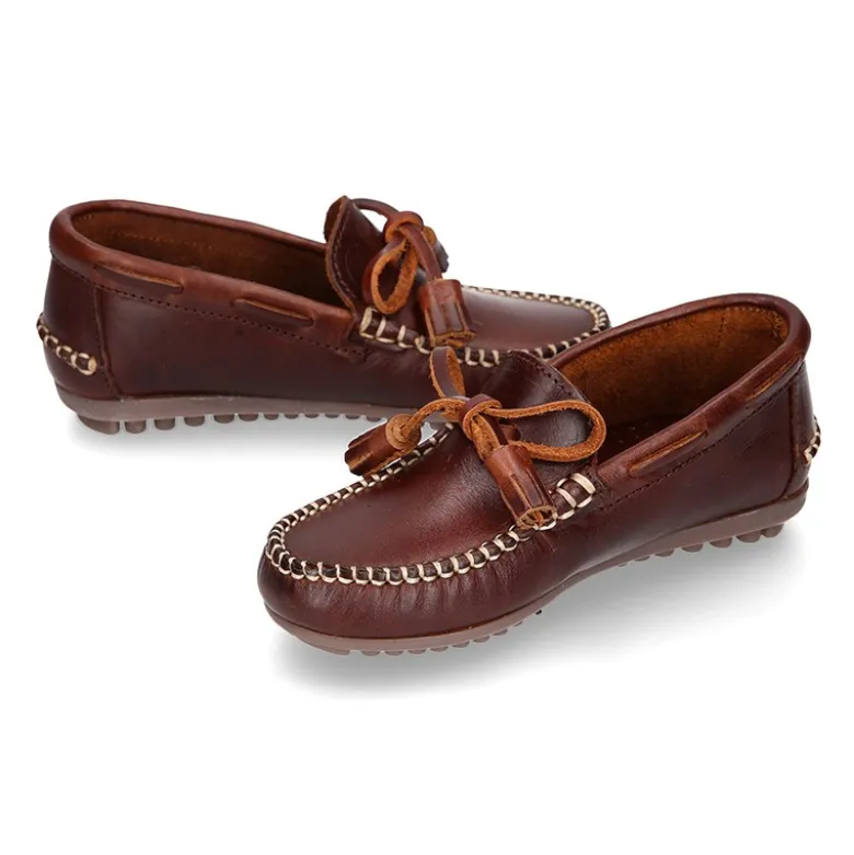Mocasín niños lazos y BORLAS en piel trabajada en color cuero.